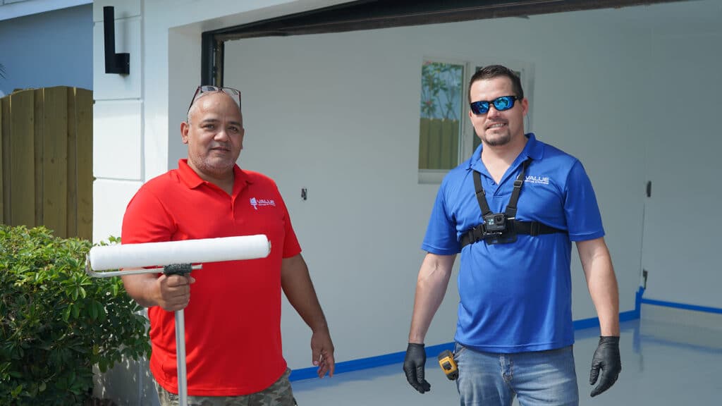 Two workers smiling in front of a garage before starting epoxy flooring project