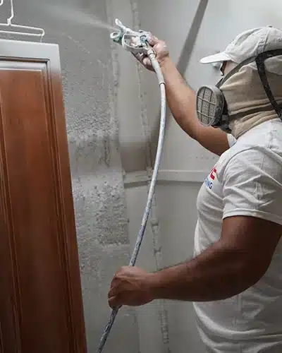 Value Painting and Flooring worker using a spray gun to paint a cabinet door