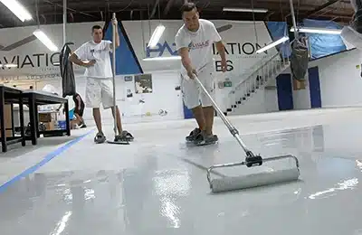Value Painting and Flooring workers applying paint on a warehouse floor