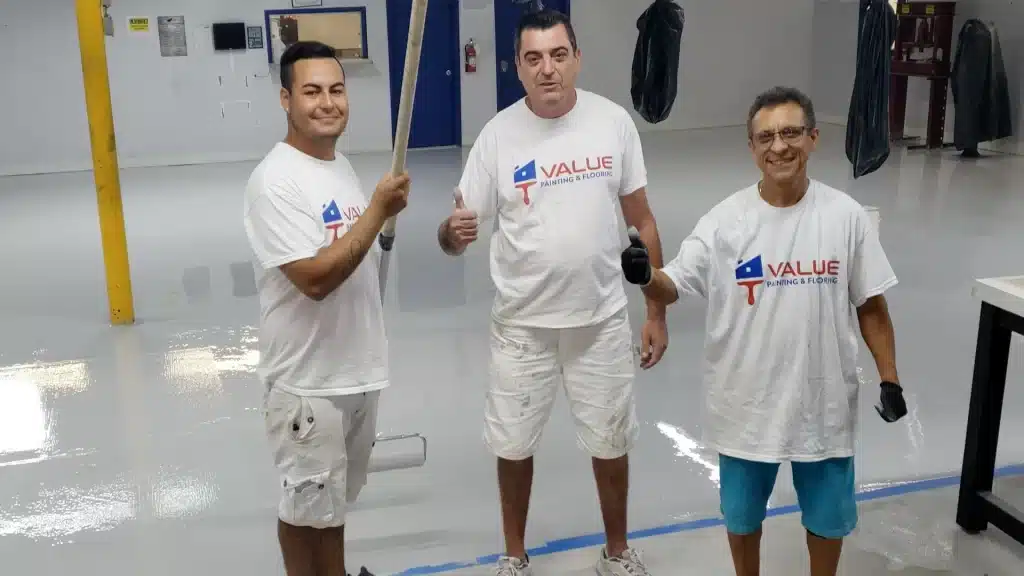 Happy Value Painting and Flooring workers posing at a warehouse floor painting project