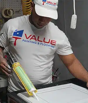 Value Painting and Flooring worker applying sealer on a cabinet door