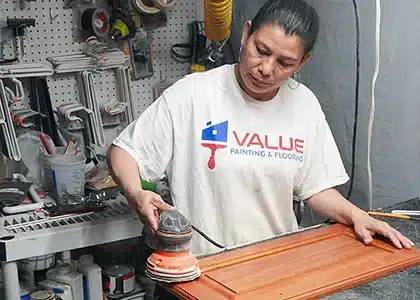 Female worker sanding a cabinet door