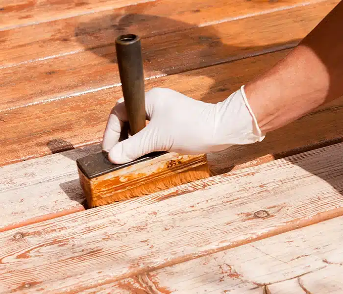 Painter applying stain on a deck.