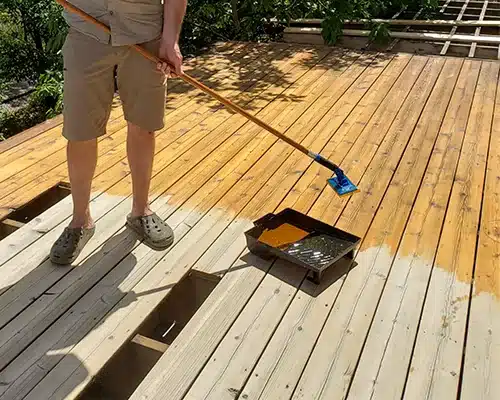 Painter staining a deck.
