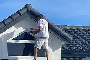 Value Painting and Flooring worker painting a window on the roof.