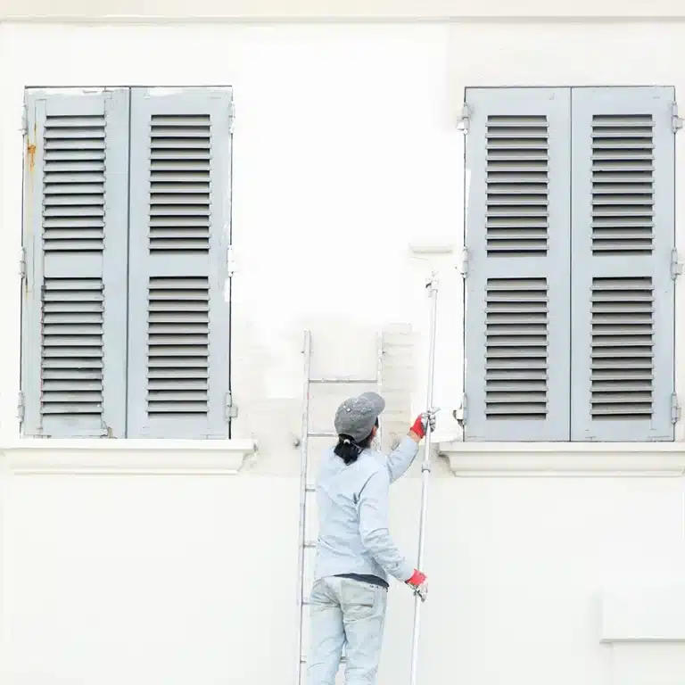 Painter performing exterior surface prep on a home