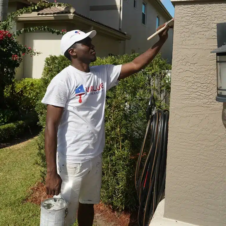 Closeup shot of Value Painting and Flooring worker performing an exterior house painting task.