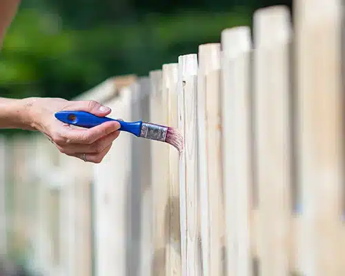 Close-up shot of a painter painting a fence.