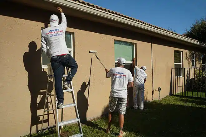 Value Painting and Flooring workers painting a wall.