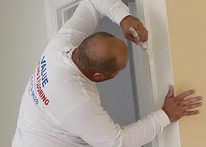 Worker painting with precision near a door during an interior house painting project