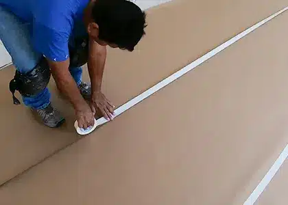 Worker prepping floor protection before an interior house painting project.