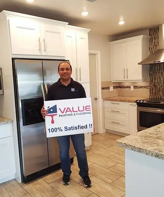 Delighted customer with '100% Satisfied' board in his newly painted kitchen