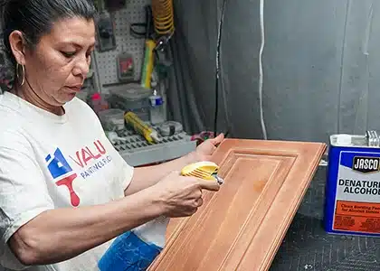 Female worker applying primer to the cabinet door