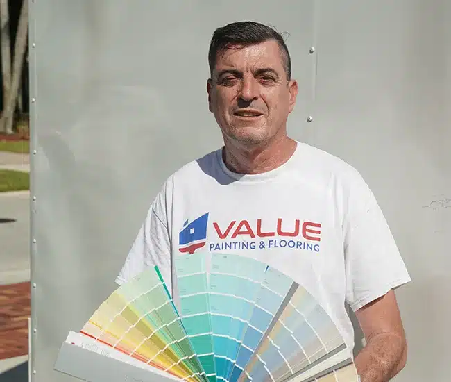Value Painting and Flooring employee holding color swatch and smiling