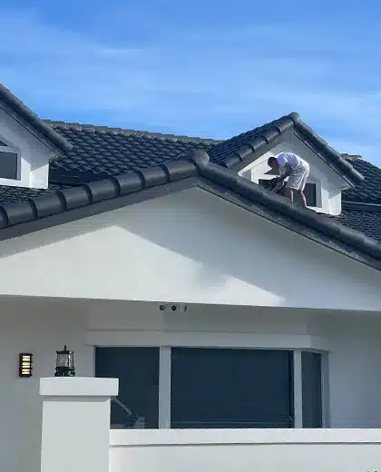 Value Painting and Flooring worker painting a home's exterior on the roof.