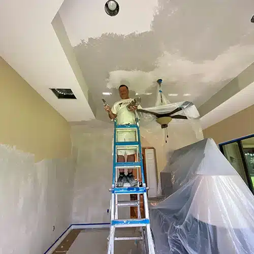 Smiling worker with scraper during popcorn ceiling removal