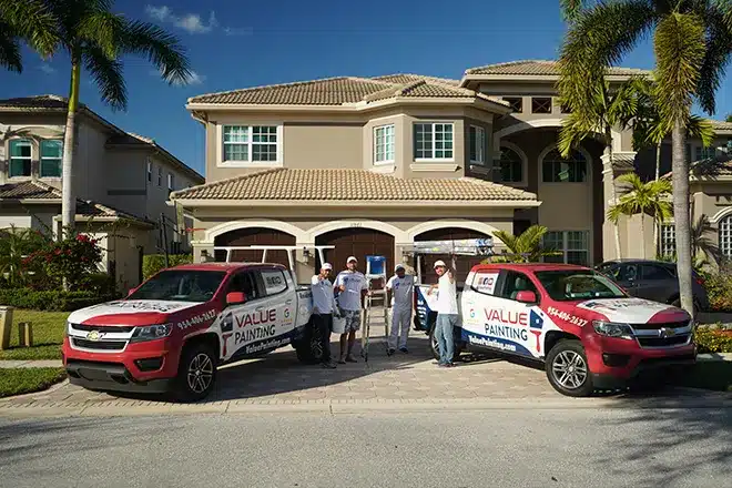 Value Painting and Flooring team posing with their service trucks in front of a beautiful home.
