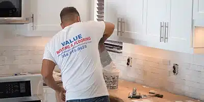 Value Painting worker installing backsplash in a kitchen.