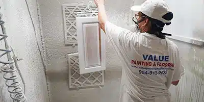 Value Painting worker spray painting a kitchen cabinet.