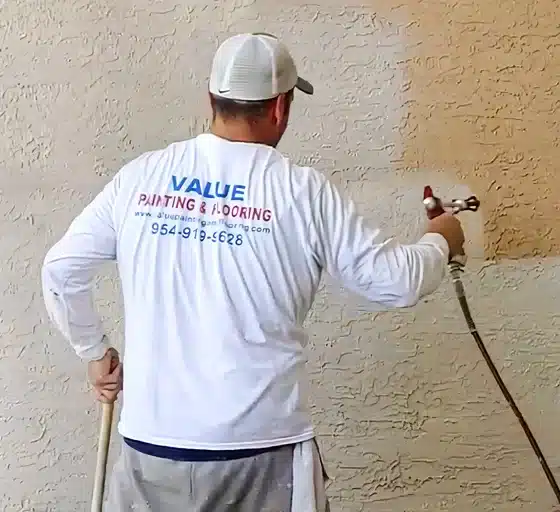 Worker from Value Painting and Flooring spray painting a home
